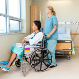 Photo of nurse standing behind patient in wheel chair looking through window.