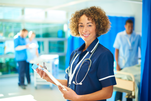 Photo of healthcare worker with clipboard smiling at camera.